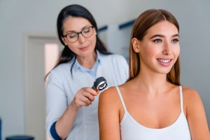 young woman at dermatologist appointment getting skin checked